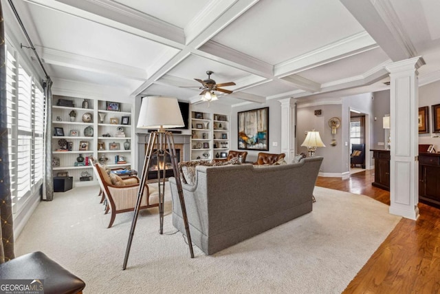 living room with beam ceiling, a glass covered fireplace, and decorative columns