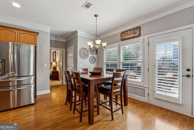 dining area with a chandelier, visible vents, baseboards, light wood-type flooring, and crown molding