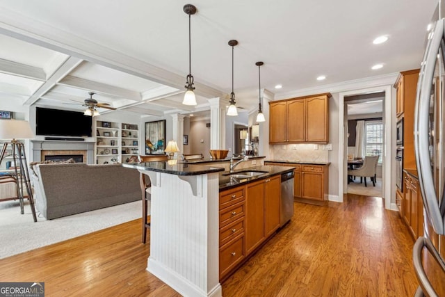 kitchen with a breakfast bar, open floor plan, stainless steel appliances, a fireplace, and a sink