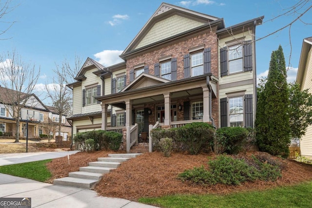 view of front of house featuring driveway, an attached garage, a porch, and brick siding