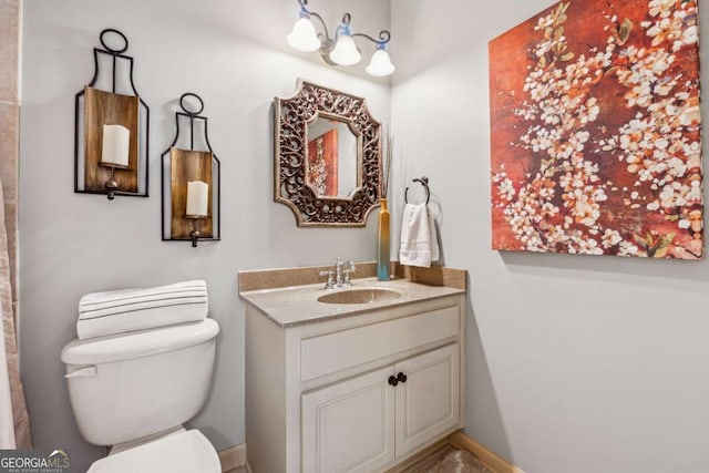 bathroom with toilet, baseboards, and vanity