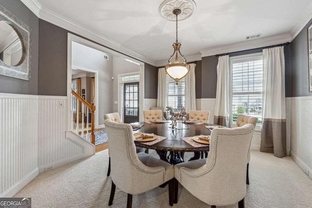 dining room with a wainscoted wall, stairs, visible vents, and light colored carpet