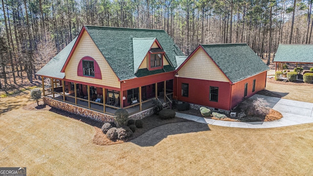 view of front of home featuring concrete driveway, crawl space, a porch, a wooded view, and a front yard