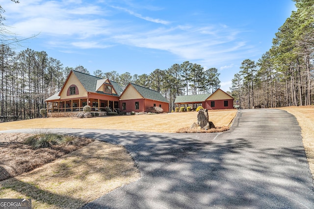 view of front of home featuring aphalt driveway, a front yard, and a porch