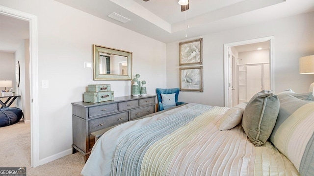 bedroom with baseboards, visible vents, light colored carpet, ensuite bathroom, and a tray ceiling