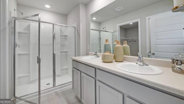 bathroom featuring a stall shower, a spacious closet, visible vents, and a sink