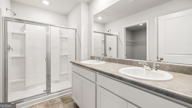 full bathroom with a stall shower, a walk in closet, a sink, and double vanity