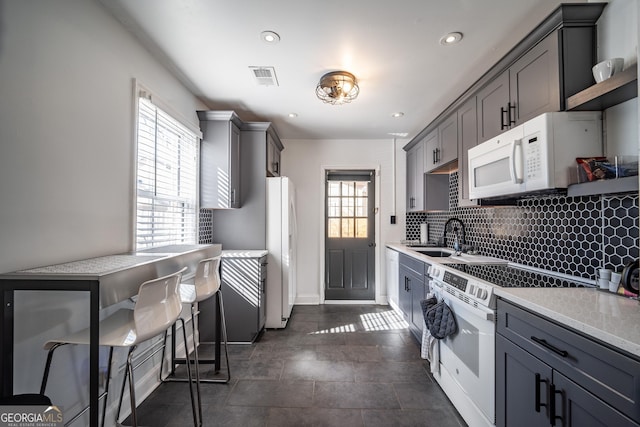 kitchen featuring white appliances, a sink, visible vents, backsplash, and gray cabinets