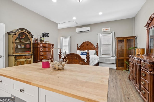 dining area featuring light wood-style floors, recessed lighting, attic access, and a wall mounted air conditioner