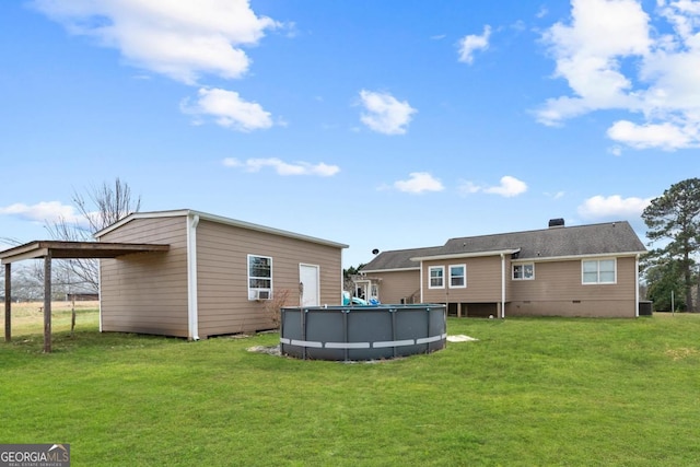 back of house with a yard, a carport, crawl space, and an outdoor pool