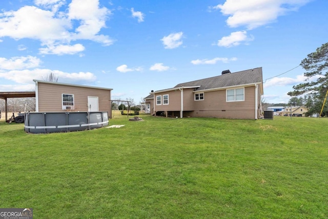 rear view of house with crawl space, an outdoor pool, and a yard