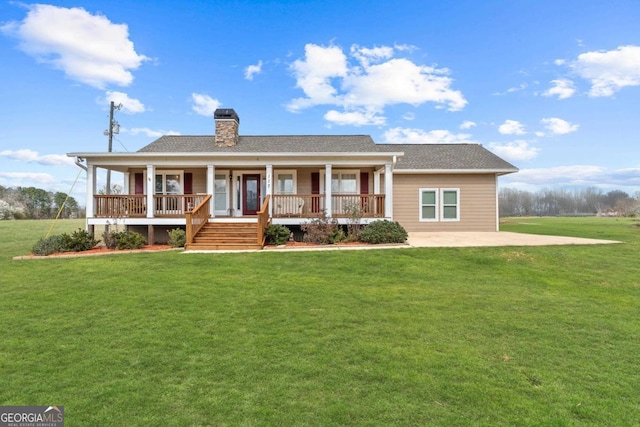 view of front of house with a shingled roof, covered porch, a chimney, and a front lawn