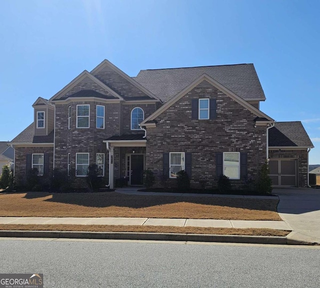 view of front of property featuring a front yard, concrete driveway, and brick siding