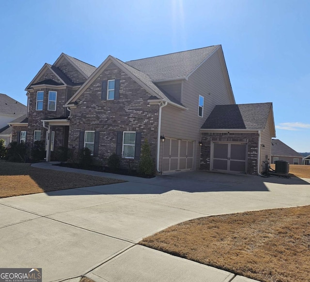 view of front of property featuring central air condition unit, driveway, an attached garage, and brick siding