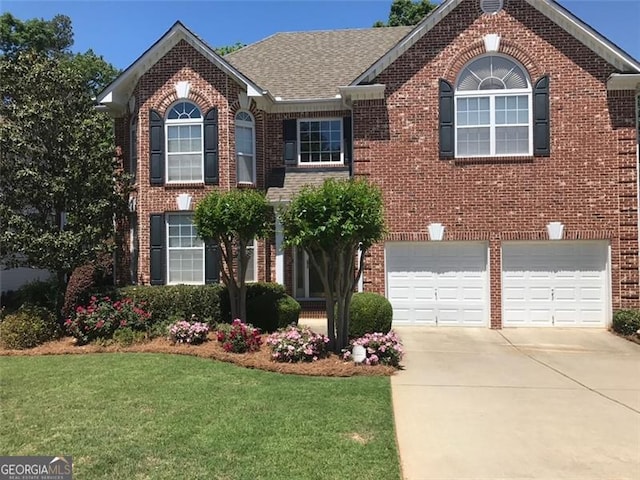 view of front of home featuring brick siding, an attached garage, concrete driveway, and a front lawn