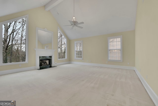 unfurnished living room with beamed ceiling, a ceiling fan, carpet floors, a premium fireplace, and baseboards