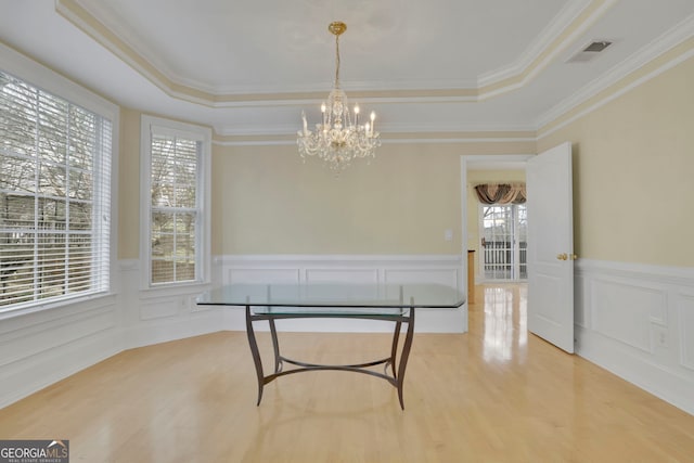 dining space with visible vents, a raised ceiling, wood finished floors, and a chandelier