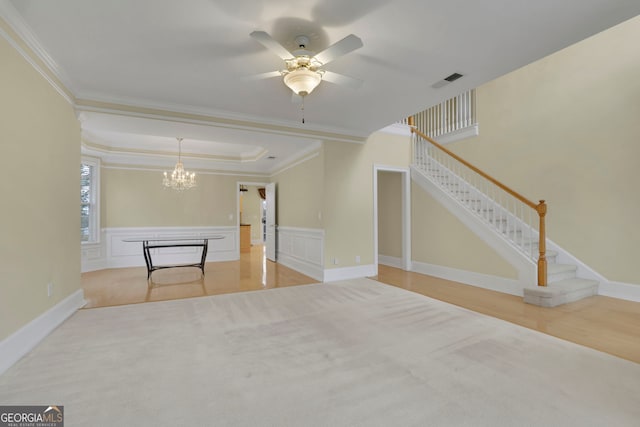 unfurnished living room featuring visible vents, stairs, ornamental molding, wainscoting, and a raised ceiling