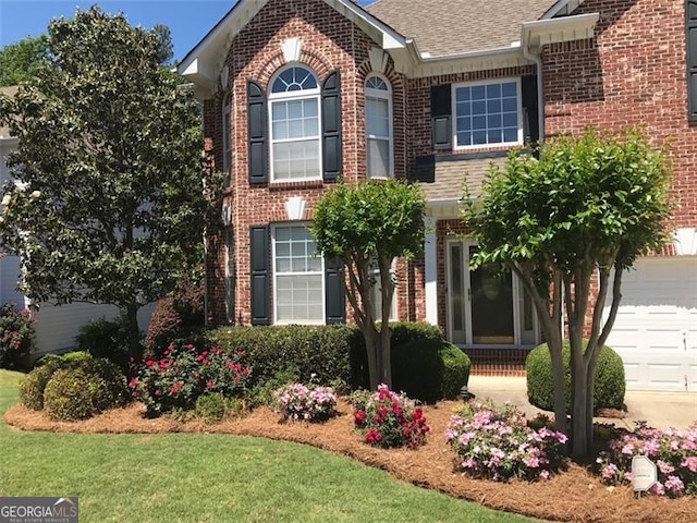 view of front of property featuring brick siding, a front yard, and a shingled roof