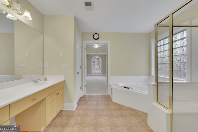 bathroom with tile patterned flooring, vanity, a bath, and a healthy amount of sunlight