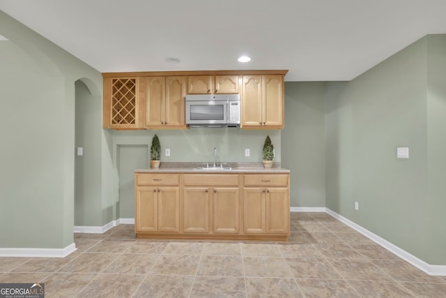 kitchen featuring light brown cabinets, a sink, recessed lighting, light countertops, and baseboards