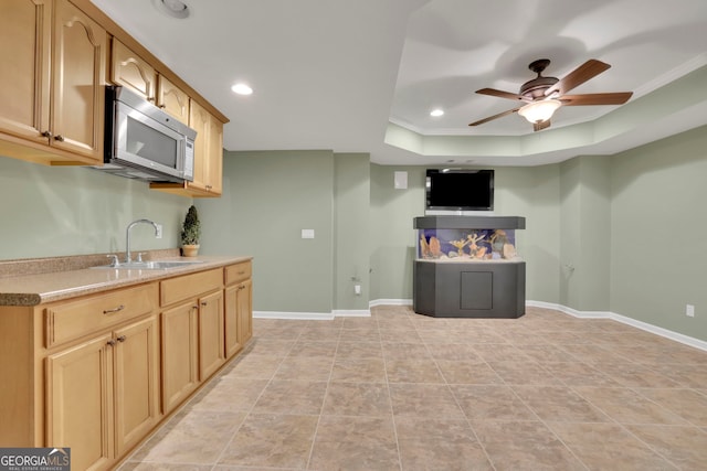 kitchen featuring stainless steel microwave, recessed lighting, a tray ceiling, and a sink