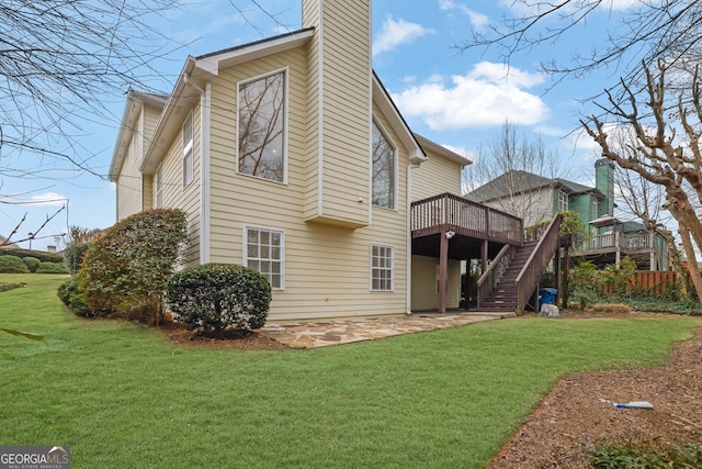 back of house featuring a wooden deck, a lawn, a patio area, and stairway