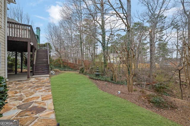 view of yard with a patio area, stairs, a deck, and fence