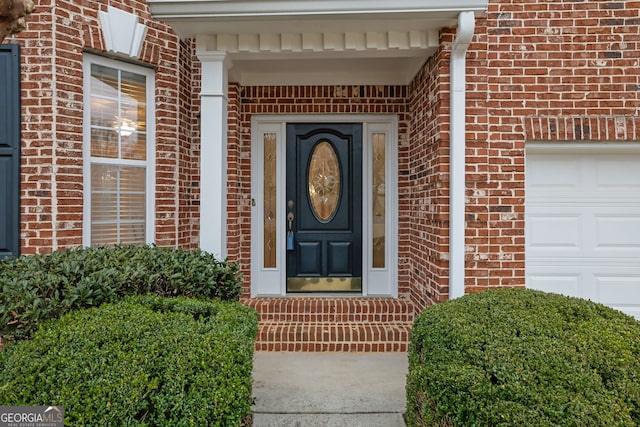 doorway to property featuring brick siding and a garage