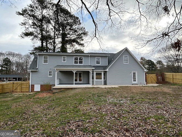 back of house with a yard, a gate, fence, and a patio