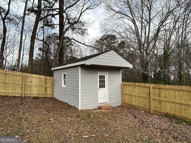 view of outdoor structure with entry steps, a fenced backyard, and an outdoor structure