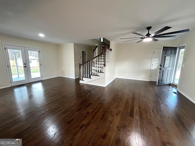 unfurnished living room with dark wood-style flooring, a healthy amount of sunlight, baseboards, and stairs