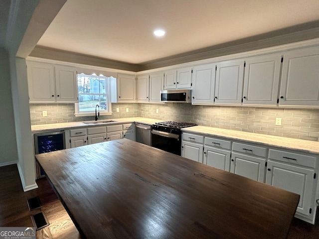 kitchen with stainless steel appliances, butcher block counters, white cabinetry, and a sink