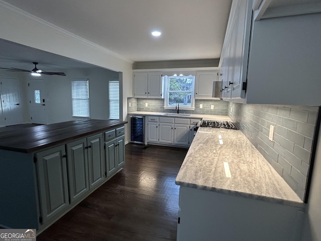 kitchen with wine cooler, dark wood-style flooring, a kitchen island, white cabinetry, and ornamental molding