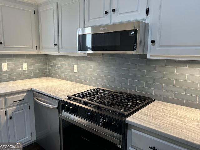 kitchen featuring black range with gas cooktop, stainless steel microwave, light countertops, and backsplash