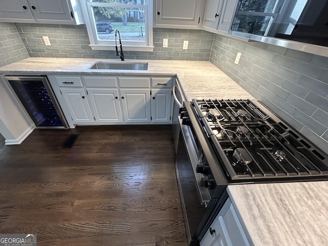 kitchen with white cabinets, dark wood-type flooring, a sink, and gas stove