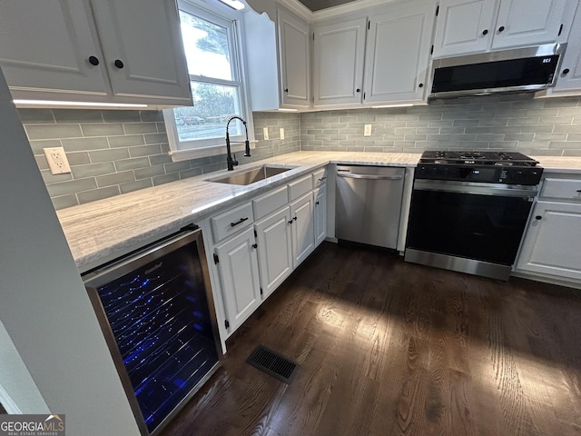 kitchen with stainless steel appliances, wine cooler, white cabinets, and a sink