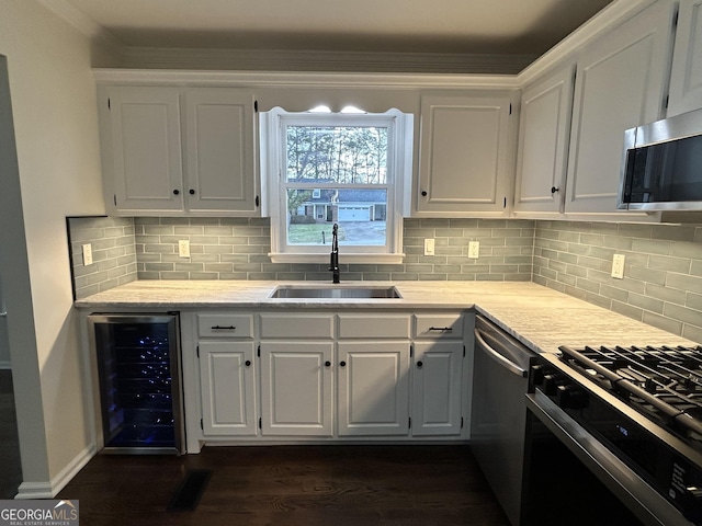 kitchen featuring wine cooler, appliances with stainless steel finishes, dark wood-type flooring, white cabinetry, and a sink