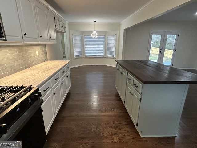 kitchen featuring gas range, white cabinets, and crown molding