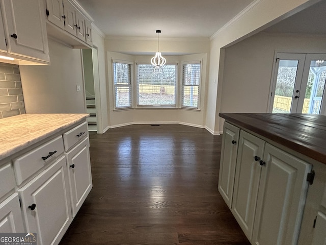 kitchen featuring dark wood-style flooring, white cabinets, crown molding, and decorative backsplash