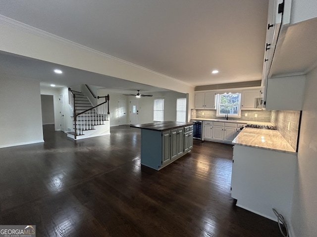 kitchen with beverage cooler, white cabinets, decorative backsplash, dark wood-style floors, and a center island