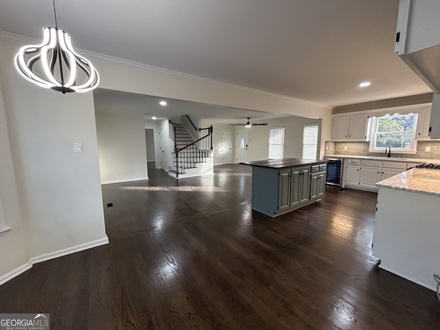 kitchen with beverage cooler, decorative backsplash, dark wood-style flooring, a center island, and a sink