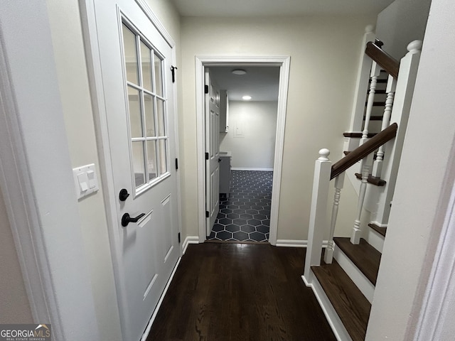 hallway featuring dark wood-type flooring, stairway, and baseboards