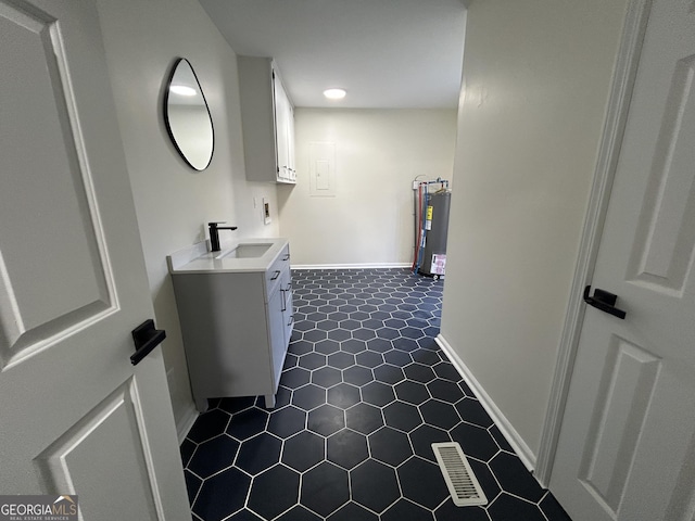 clothes washing area featuring baseboards, visible vents, hookup for an electric dryer, water heater, and a sink