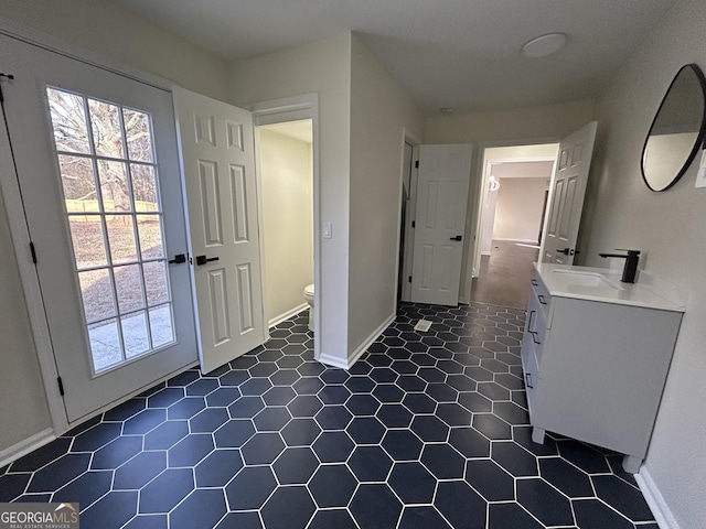 interior space with tile patterned floors, vanity, toilet, and baseboards