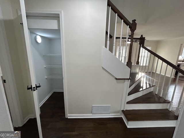 staircase with baseboards, visible vents, and wood finished floors