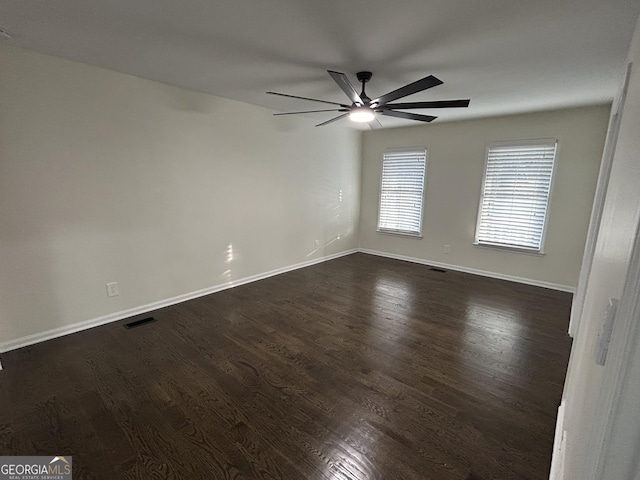 empty room with baseboards, visible vents, ceiling fan, and dark wood-style flooring