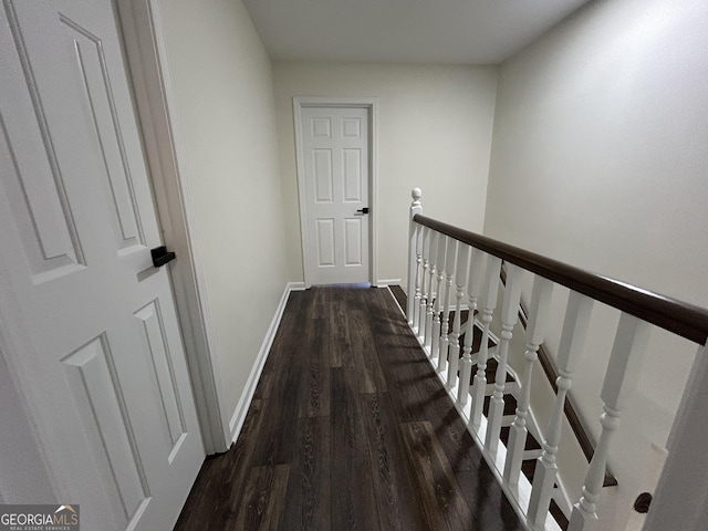 hallway featuring dark wood-style floors, an upstairs landing, and baseboards