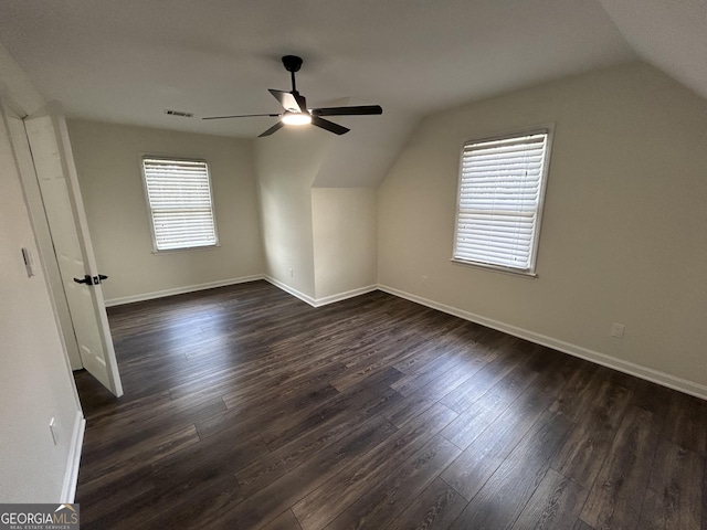 additional living space with dark wood-type flooring, visible vents, vaulted ceiling, and baseboards