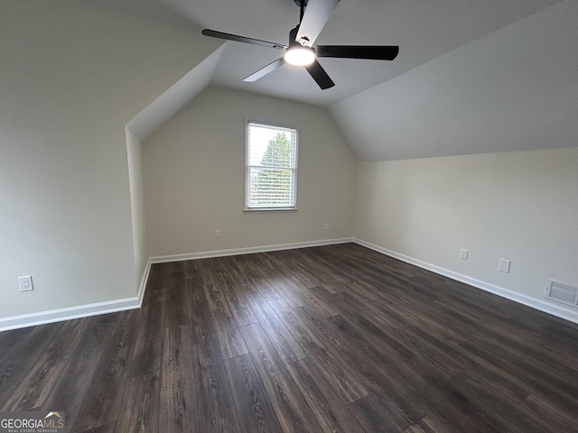 additional living space with baseboards, visible vents, ceiling fan, dark wood-style flooring, and vaulted ceiling